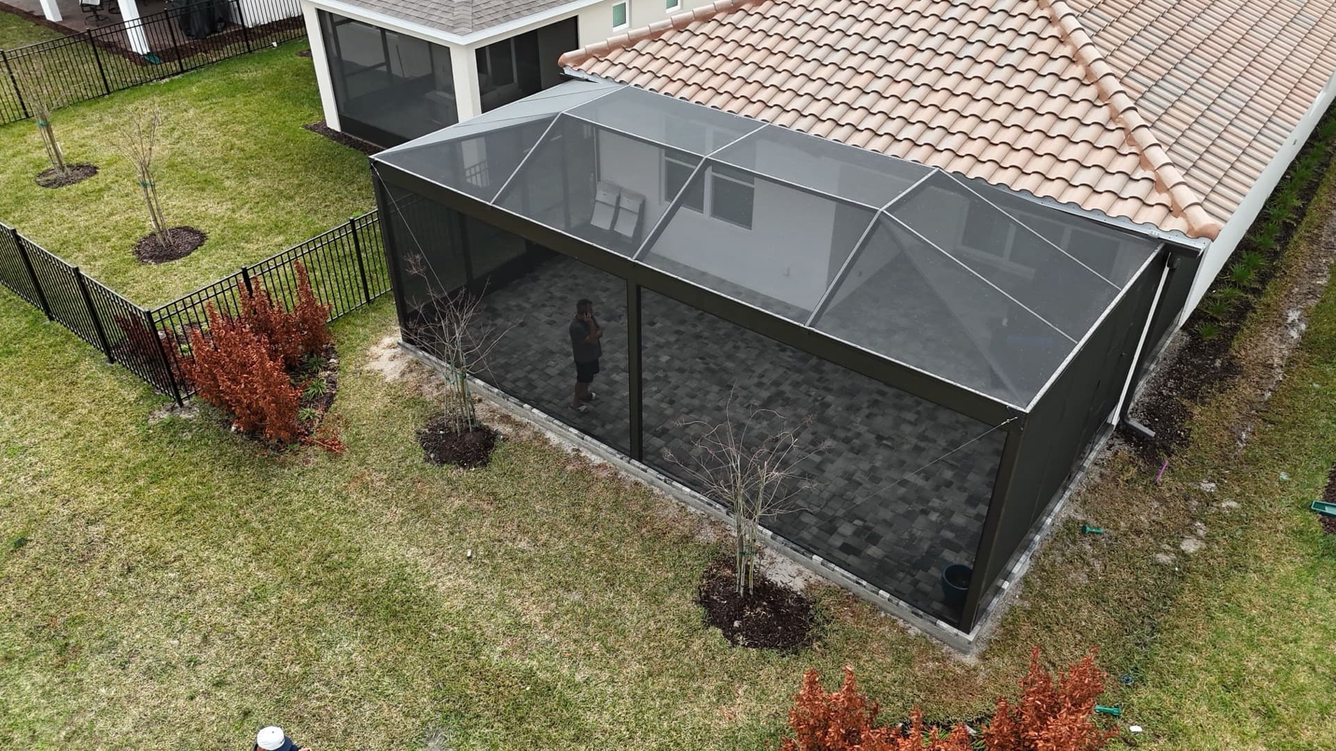 Aerial view of a black aluminum picket fence enclosing a backyard with a screen room