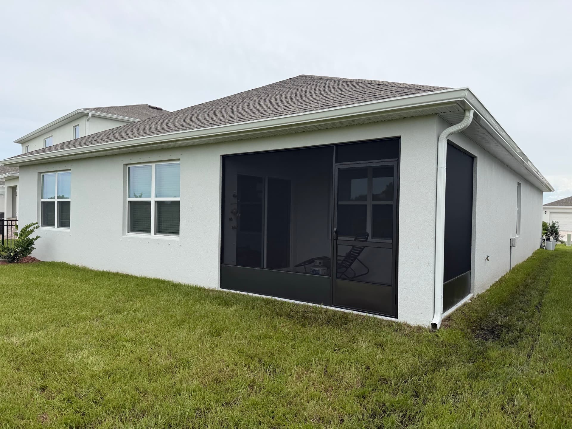 Seamless gutter run and downspout above a screened lanai on a Florida home